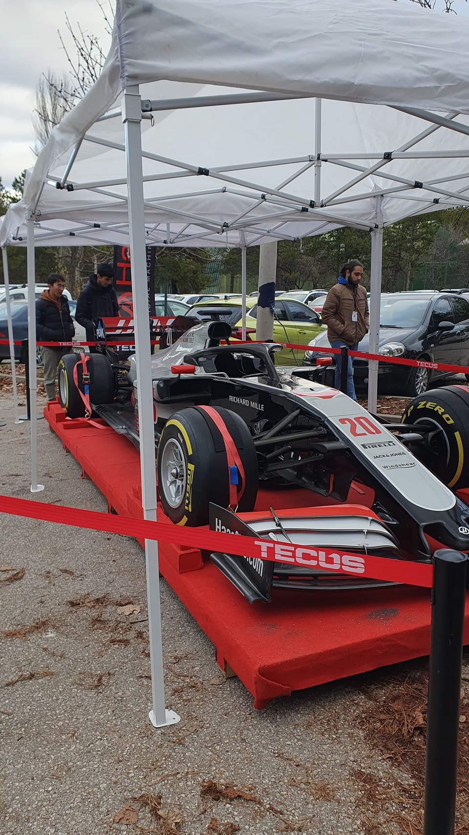 A Formula 1 car on a red display ramp under a marquee on the ODTU campus.