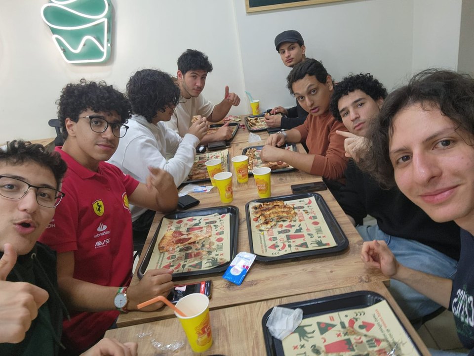 Abdullah and six friends crowded around a table of food, all pulling faces at the camera.
