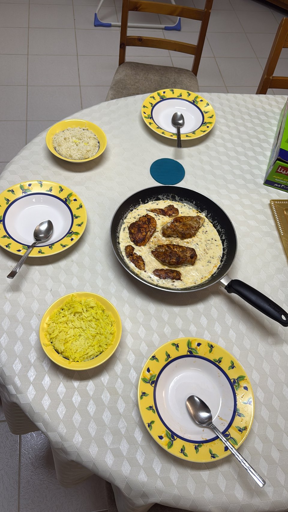 A table laid with rice, stew and side dishes on patterned plates, cooked at home.